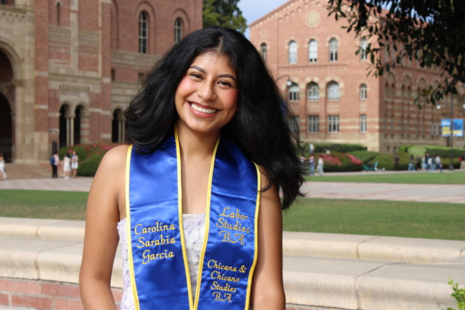 Carolina Sarabia Garcia smiling in a graduation portrait in front of Royce Hall at UCLA