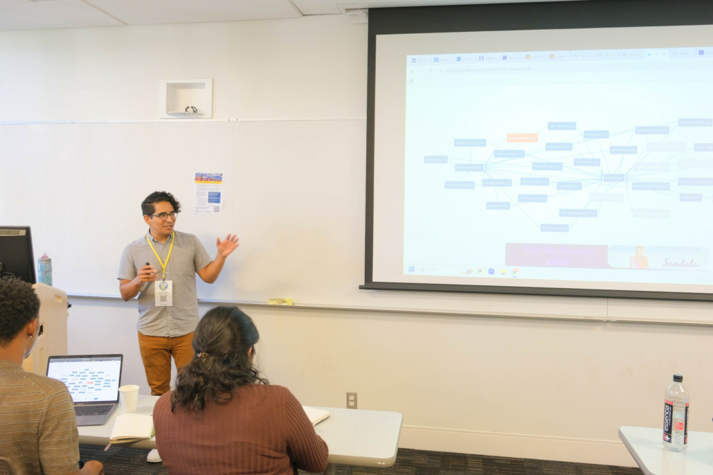 Joel Montano leads the "Researching Property Ownership" workshop at the front of a classroom in front of a slideshow showing a box data map