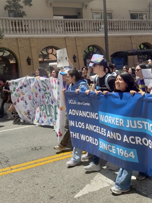 Tanveer Sandal (center) holds the UCLA Labor Center banner alongside peers / UCLA Labor Studies